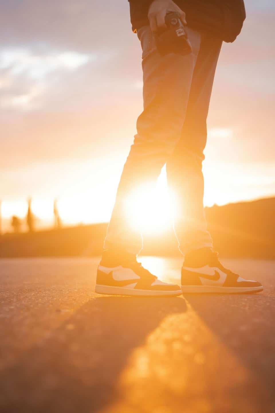 Person holding a camera while standing on asphalt outdoors.