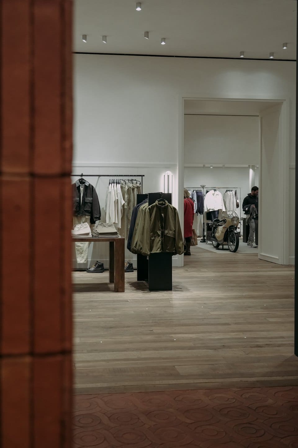 Modern boutique with clothing displays and a vintage motorcycle.