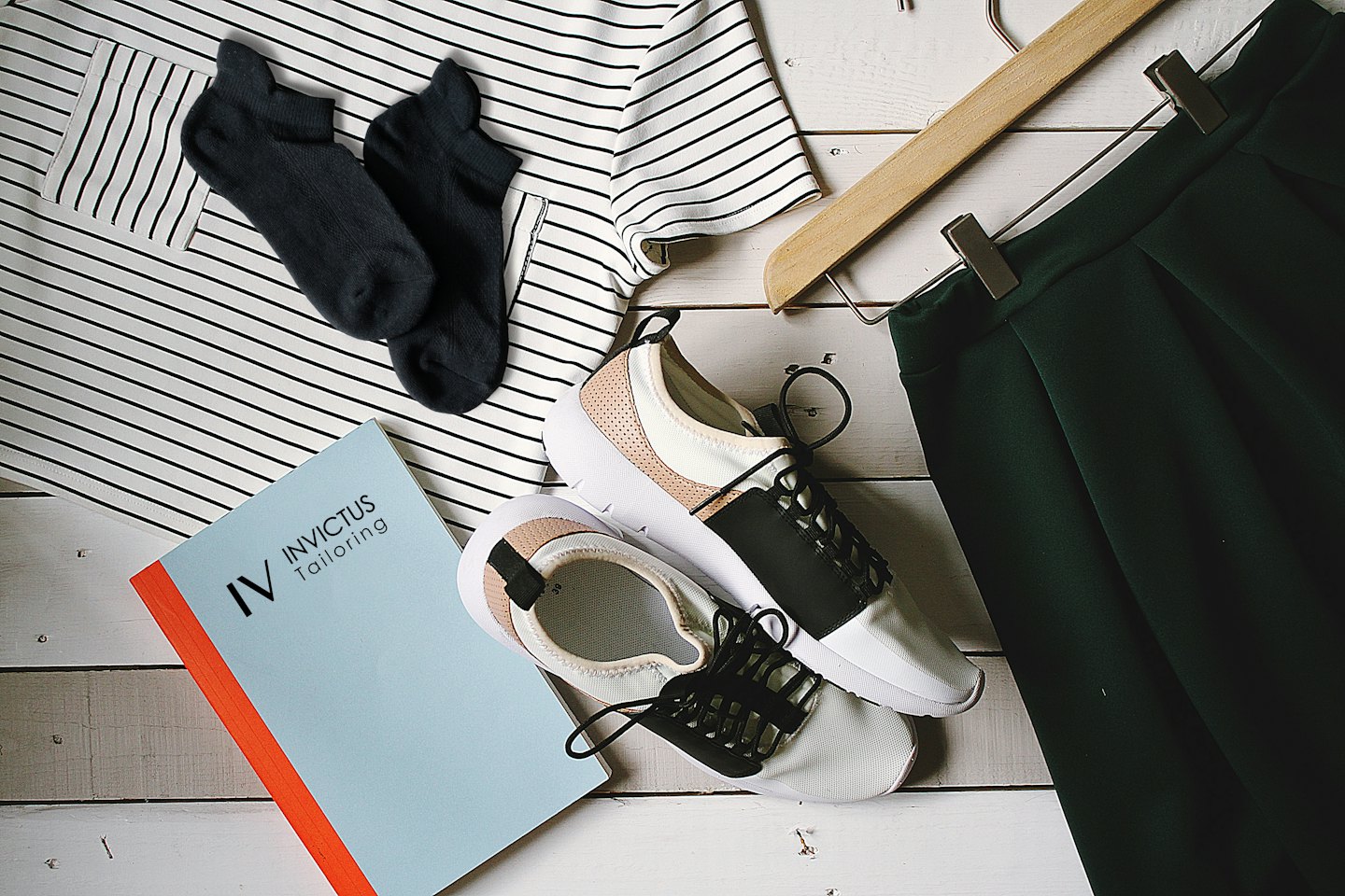 Casual clothing and a notebook arranged on a wooden surface.
