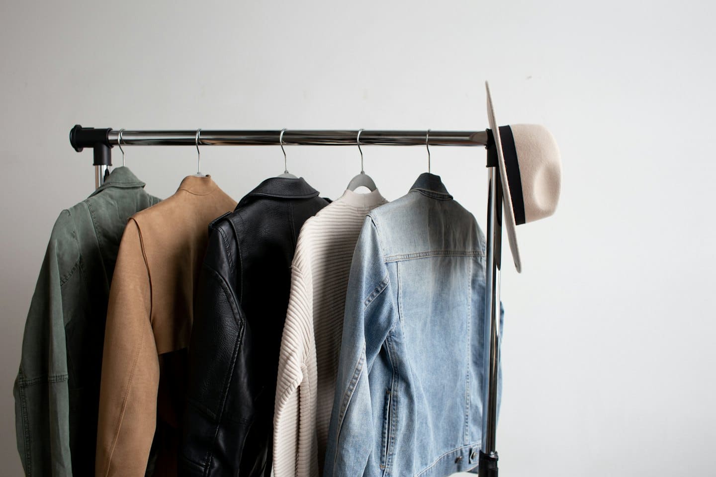Stylish jackets and a fedora on a modern clothing rack.