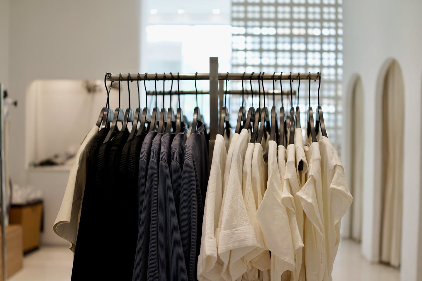 Black, grey, and cream garments hang on a retail rack.