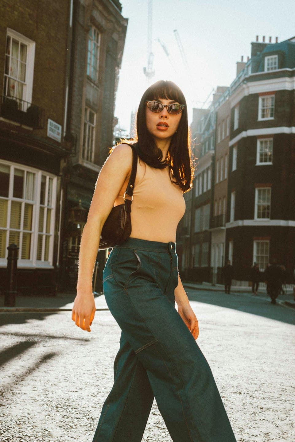 Woman walks down a sunny city street towards the camera.